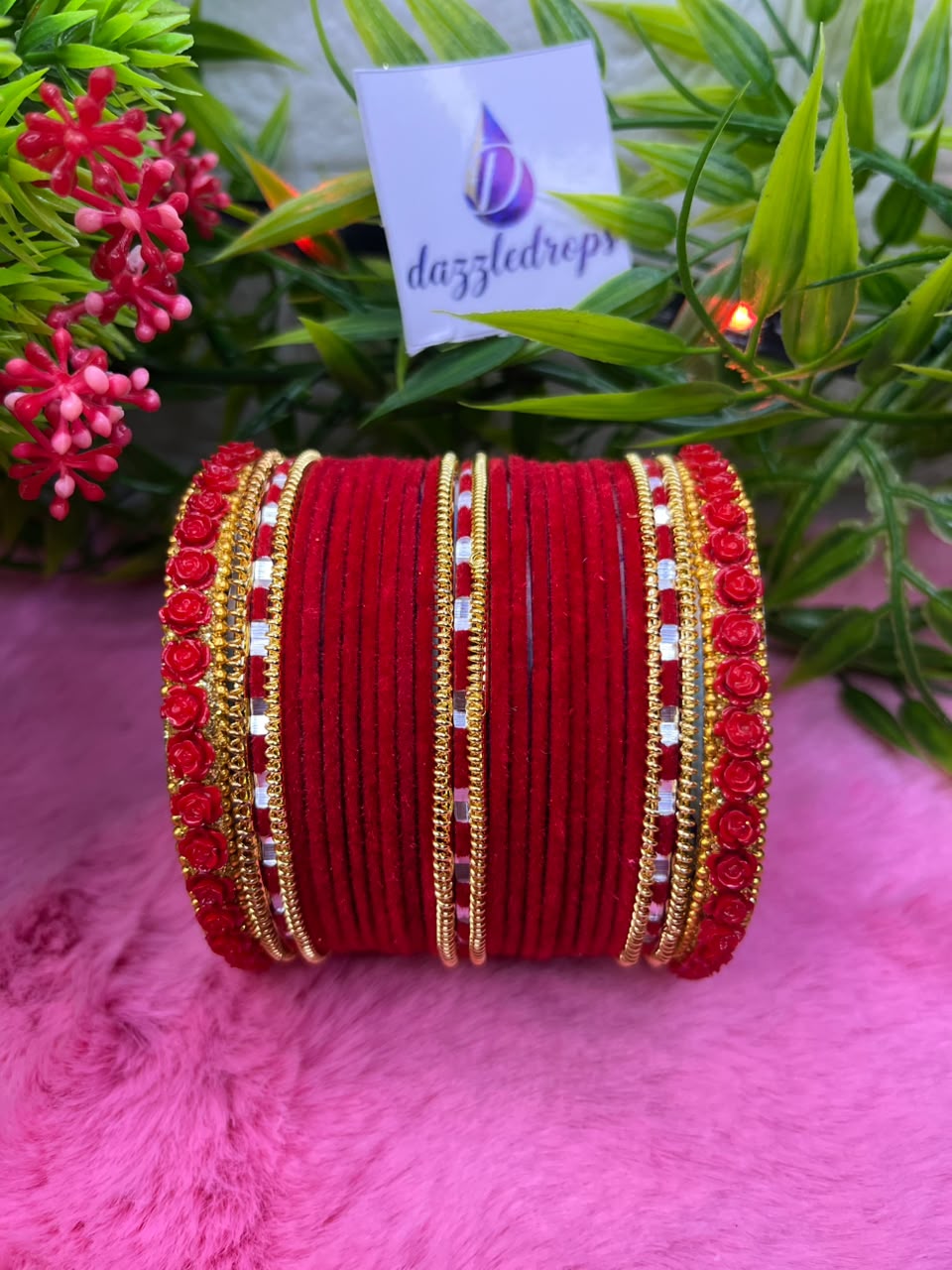 Teal green, pink, and red velvet bangle stacks with gold rose motifs and mirror work displayed on a pink background.