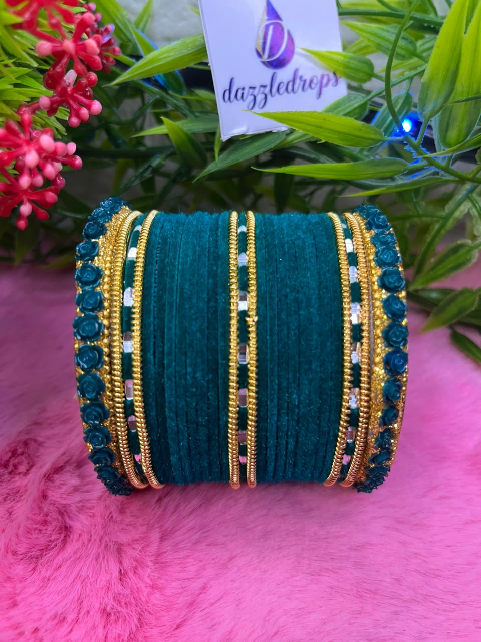 Teal green, pink, and red velvet bangle stacks with gold rose motifs and mirror work displayed on a pink background. — view 2