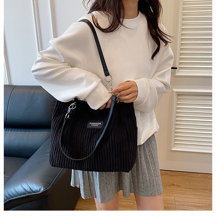 Woman wearing white sweatshirt carrying Korean black corduroy shoulder tote bag — view 3
